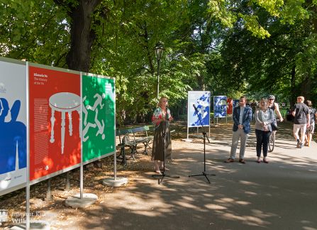 fotografia. wystawa Wyszehrad to ludzie na krakowskich plantach. ludzie przechadzają się pomiędzy plakatami ustawionymi w rzędzie wzdłuż alejki.